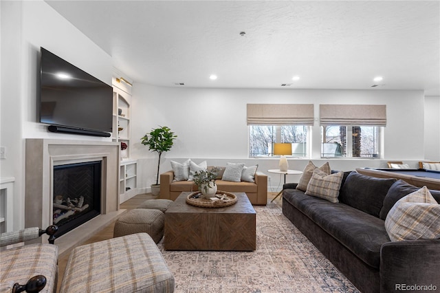 living room featuring built in features, recessed lighting, a fireplace, and visible vents