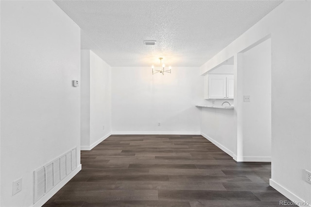 7220 S Gaylord St Unit G17, Littleton, CO 80122 - unfurnished dining area with a chandelier, a textured ceiling, dark wood-type flooring, and baseboards