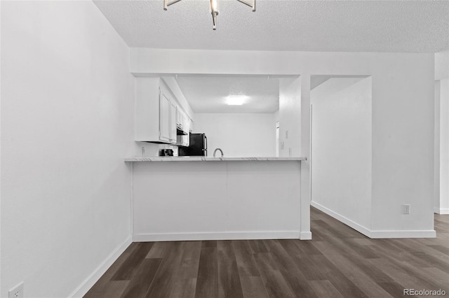 7220 S Gaylord St Unit G17, Littleton, CO 80122 - kitchen featuring a textured ceiling, dark wood-style flooring, freestanding refrigerator, baseboards, and white cabinets