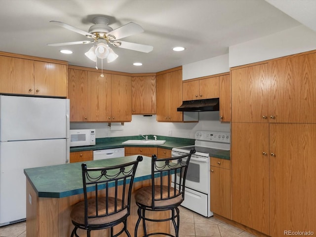 5660 S Eaton St, Littleton, CO 80123 - kitchen with white appliances, under cabinet range hood, dark countertops, a sink, and a breakfast bar area