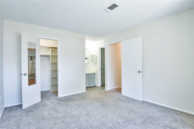 7185 S Gaylord St Unit A, Littleton, CO 80122 - unfurnished bedroom with carpet flooring, a walk in closet, a textured ceiling, ensuite bathroom, and baseboards