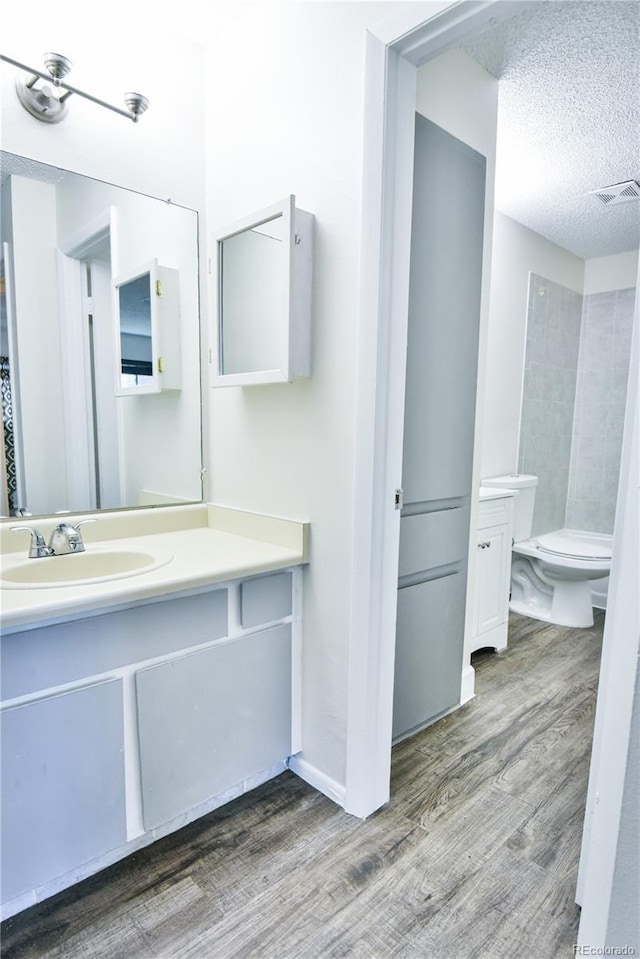 7185 S Gaylord St Unit A, Littleton, CO 80122 - bathroom with wood finished floors, vanity, toilet, a textured ceiling, and a shower