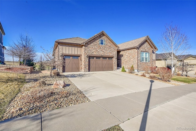 view of front of property featuring board and batten siding, stone siding, a garage, and concrete driveway