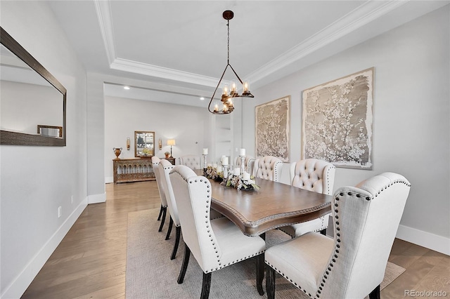 dining room featuring ornamental molding, a tray ceiling, and wood finished floors