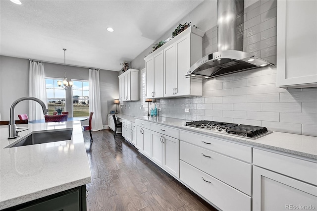 kitchen featuring stainless steel gas cooktop, dark wood-type flooring, a sink, wall chimney range hood, and decorative backsplash