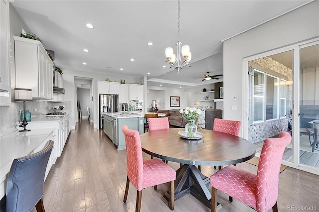 dining room featuring recessed lighting, light wood finished floors, and ceiling fan with notable chandelier