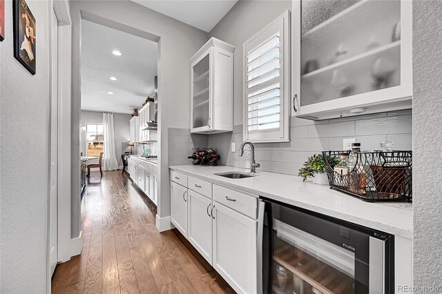 kitchen featuring tasteful backsplash, dark wood-type flooring, white cabinets, a sink, and beverage cooler