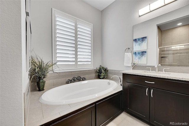 bathroom featuring tile patterned flooring, a garden tub, a shower stall, and vanity