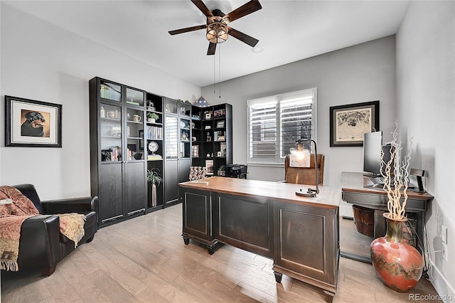 home office with light wood-style flooring and a ceiling fan