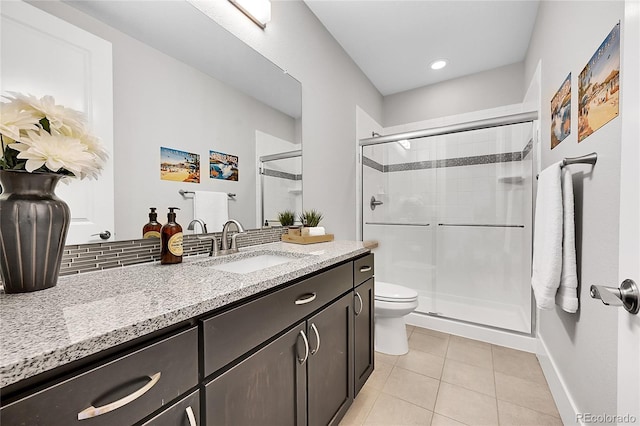 bathroom featuring tile patterned flooring, toilet, vanity, a shower stall, and decorative backsplash