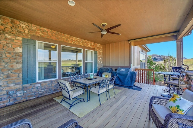 wooden terrace with a ceiling fan and outdoor dining space