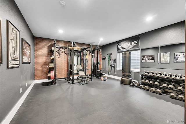 workout area with brick wall, baseboards, and recessed lighting