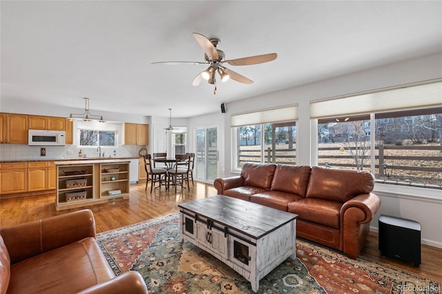 living room featuring ceiling fan, sink, and light hardwood / wood-style flooring