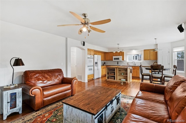 living room with ceiling fan, sink, and light hardwood / wood-style flooring