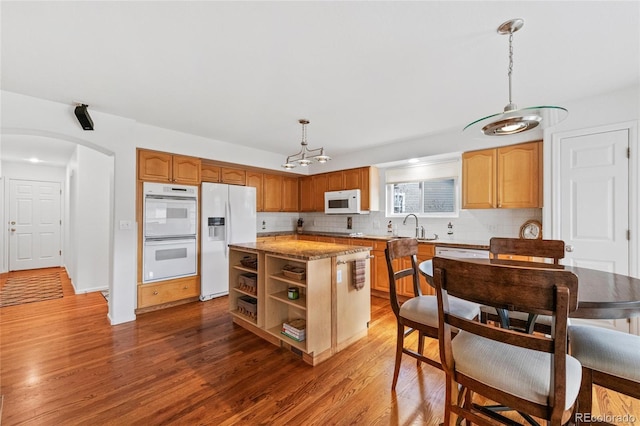 kitchen featuring sink, a center island, hanging light fixtures, dark hardwood / wood-style floors, and white appliances