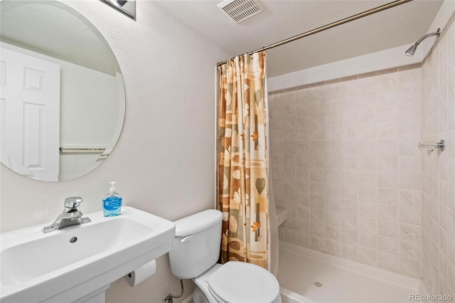 bathroom featuring walk in shower, toilet, and sink