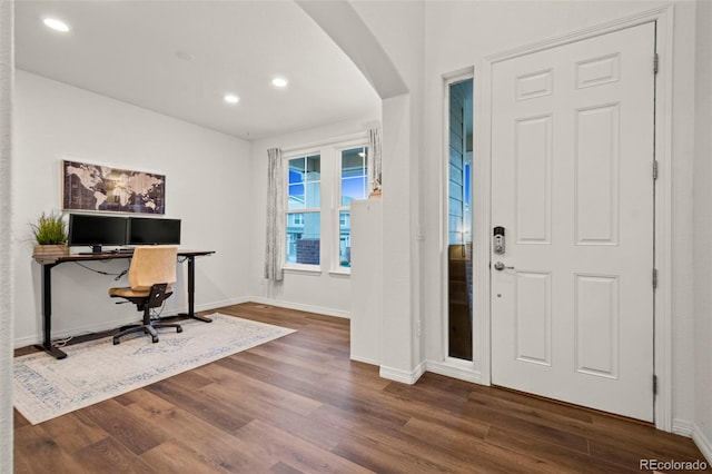 foyer entrance featuring baseboards, arched walkways, dark wood-type flooring, and recessed lighting