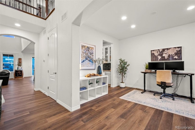 home office with arched walkways, visible vents, baseboards, and wood finished floors