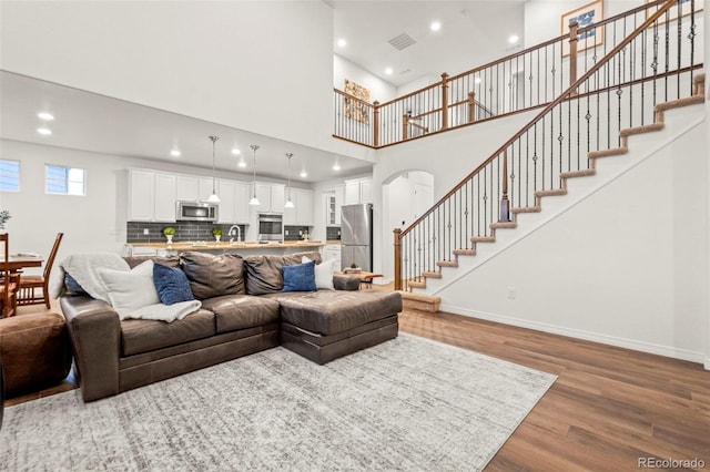 living room with recessed lighting, wood finished floors, visible vents, baseboards, and stairway