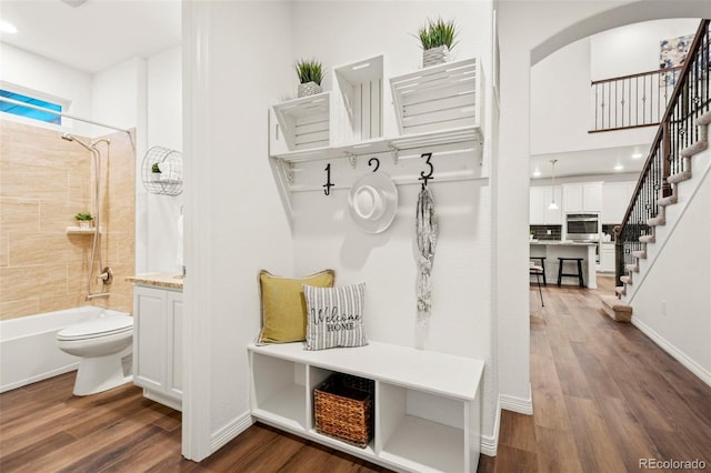 mudroom featuring arched walkways, dark wood finished floors, and baseboards