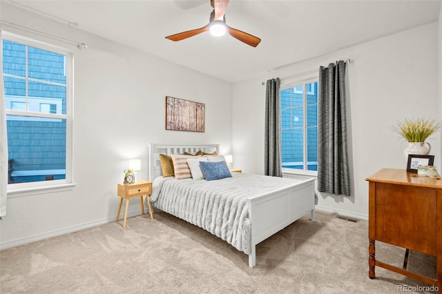 bedroom featuring baseboards, a ceiling fan, visible vents, and light colored carpet