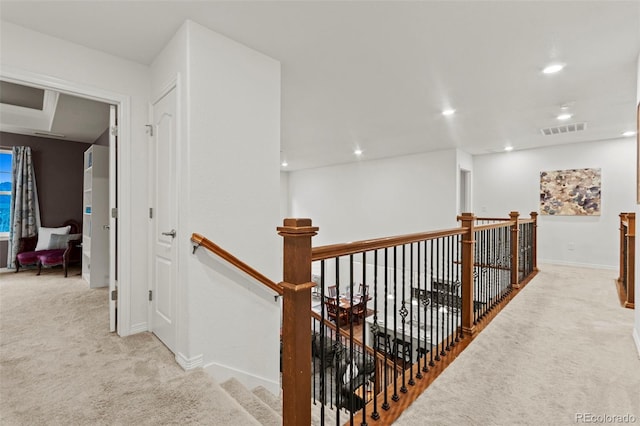 corridor with carpet floors, recessed lighting, visible vents, and an upstairs landing