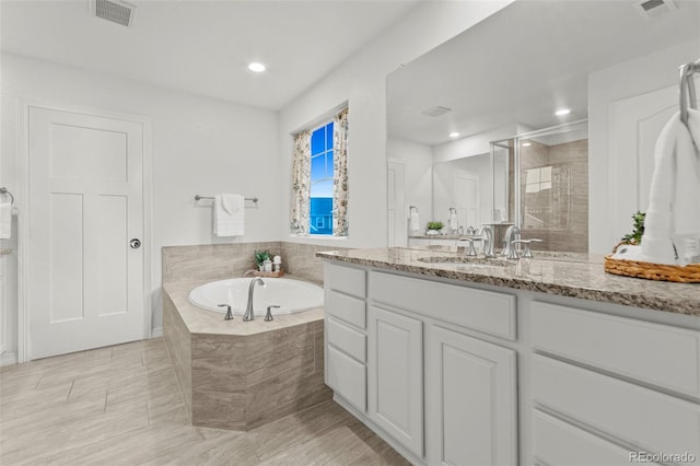 bathroom featuring a stall shower, visible vents, a bath, and vanity