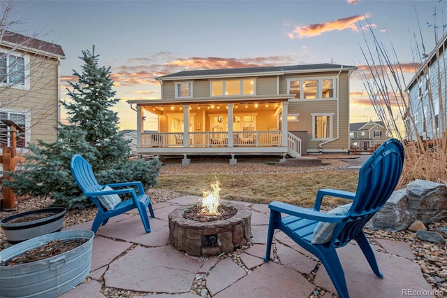 back of house at dusk featuring a fire pit, a patio area, and a wooden deck