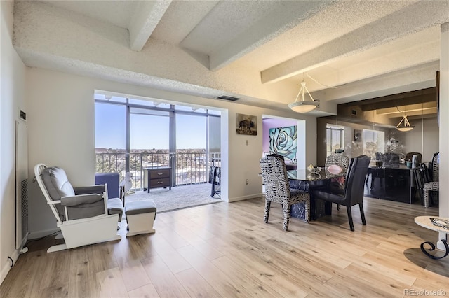 dining space with beam ceiling, a textured ceiling, and hardwood / wood-style flooring