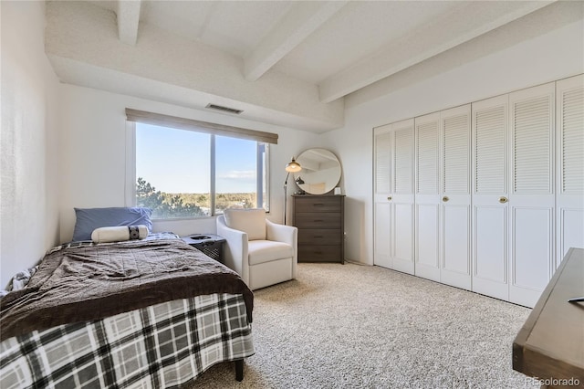 carpeted bedroom featuring beamed ceiling and a closet