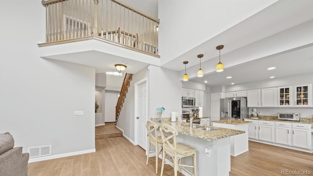kitchen featuring glass insert cabinets, visible vents, white cabinetry, a towering ceiling, and appliances with stainless steel finishes