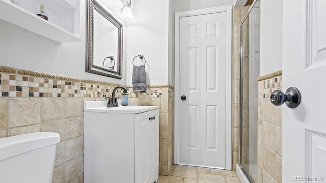bathroom featuring toilet, a stall shower, tile walls, wainscoting, and vanity