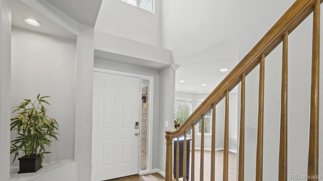 foyer entrance with stairway, wood finished floors, and recessed lighting