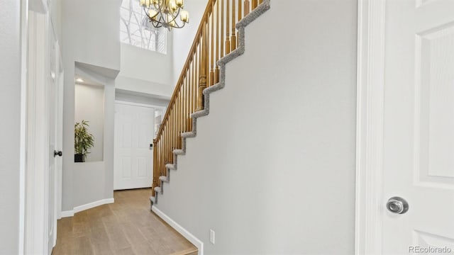 foyer entrance with an inviting chandelier, stairway, wood finished floors, and baseboards