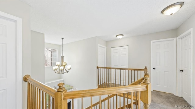 corridor with an upstairs landing, a chandelier, and carpet