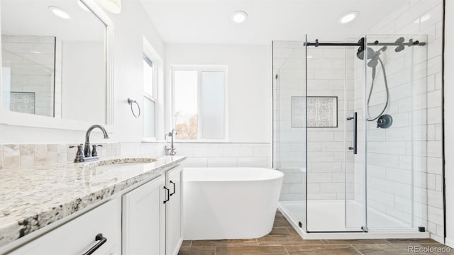 full bath featuring a stall shower, recessed lighting, vanity, and a freestanding bath