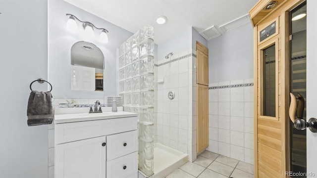 full bathroom with tile walls, tile patterned flooring, vanity, and tiled shower