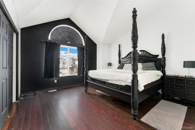 bedroom with vaulted ceiling, dark wood-type flooring, and a closet