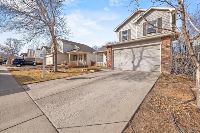 traditional-style house featuring a garage, covered porch, concrete driveway, and brick siding