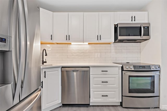 kitchen with sink, stainless steel appliances, white cabinetry, and backsplash