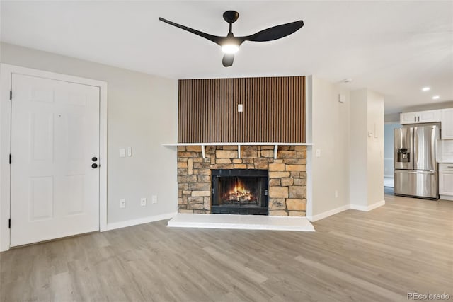 unfurnished living room with light wood-type flooring, ceiling fan, and a fireplace