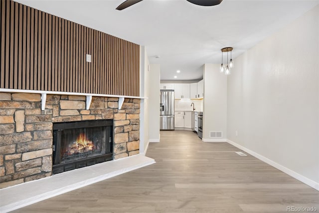 unfurnished living room with ceiling fan, light hardwood / wood-style floors, and a fireplace