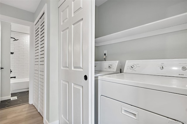 laundry area with washing machine and dryer and light hardwood / wood-style flooring