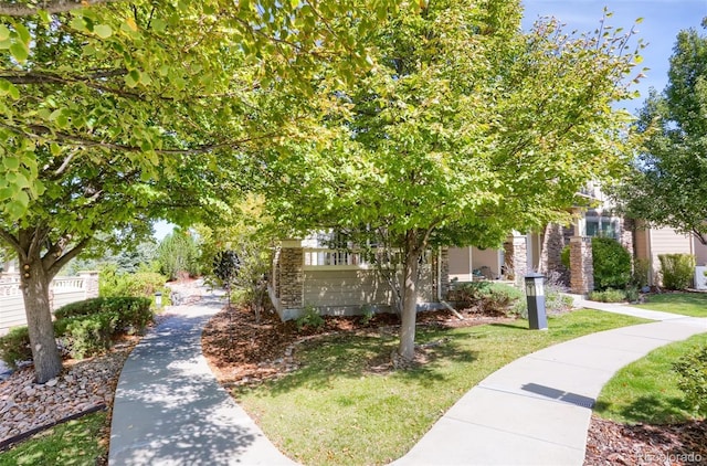 obstructed view of property featuring stone siding and a front lawn