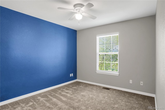 carpeted spare room featuring visible vents, ceiling fan, and baseboards