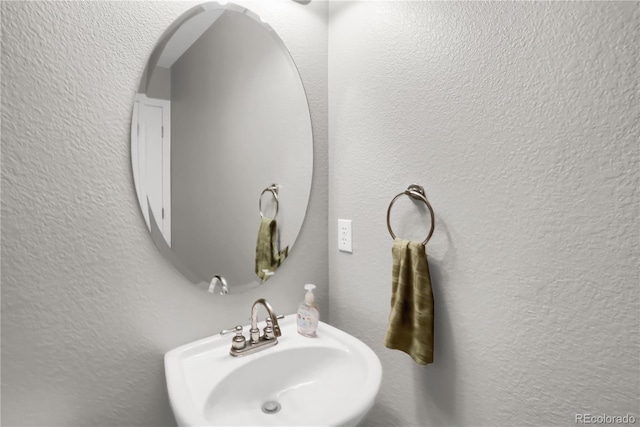 bathroom featuring a sink and a textured wall