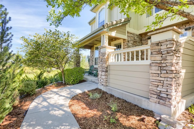 view of home's exterior with covered porch, stone siding, and board and batten siding