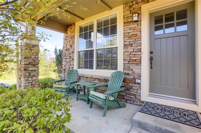 view of exterior entry with a porch and stone siding