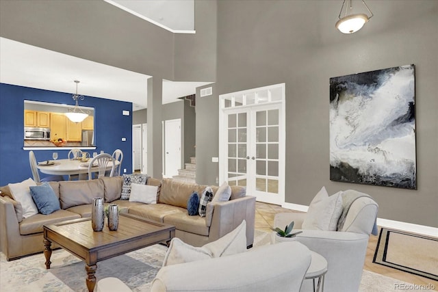 living room with visible vents, baseboards, a towering ceiling, stairs, and french doors