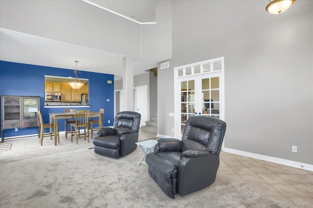 living area with light tile patterned floors, baseboards, a high ceiling, stairs, and french doors